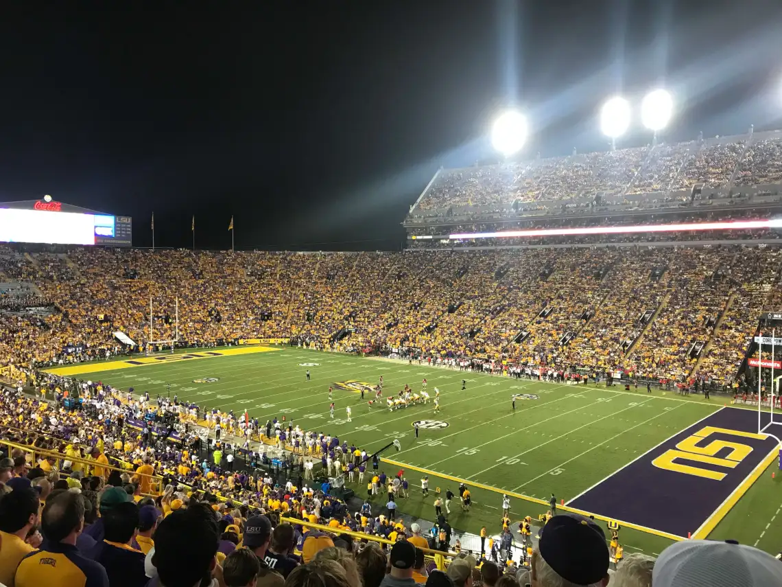 LSU Tiger Stadium packed with fans in purple and gold during a night football game